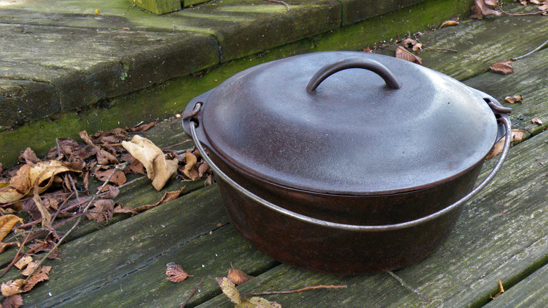 Antique cast iron Dutch oven on a weathered, slatted wood surface
