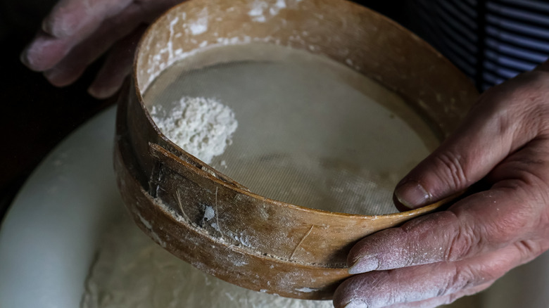 hands sifting flour close up