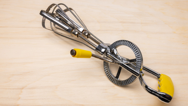 A hand crank egg beater on a wood table