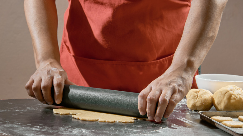 Close-up of a cook rolling out dough for baking