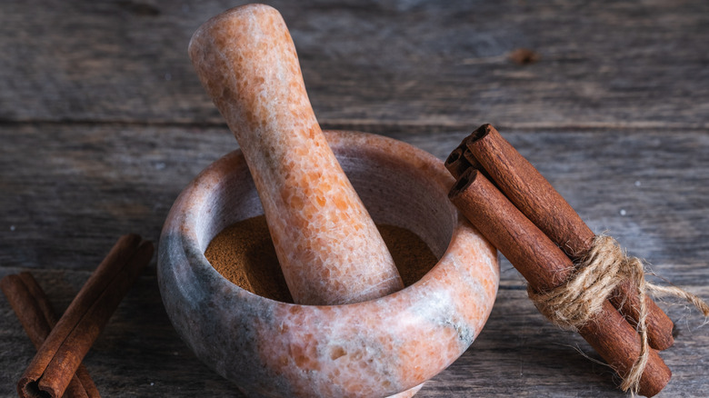 A speckled stone mortar and pestle with cinnamon