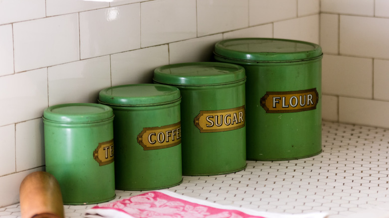 A collection of green antique tin canisters for tea, coffee, sugar, and flour