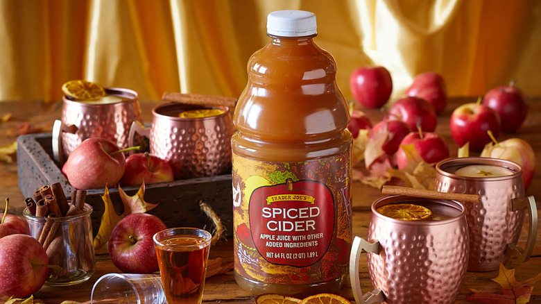 bottle of Trader Joe's Spiced Cider set on table surrounded by copper mugs