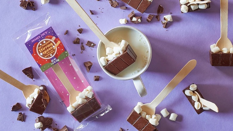 Five Trader Joe's Hot Chocolate Stirring Spoons on a table, with one in a mug of hot milk