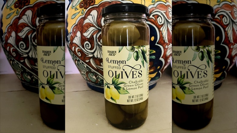 A jar of Trader Joe's Lemon Stuffed Olives on a table in front of a vase