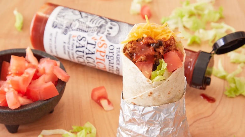 A bottle of Trader Joe's Organic Spicy Taco Sauce next to a burrito