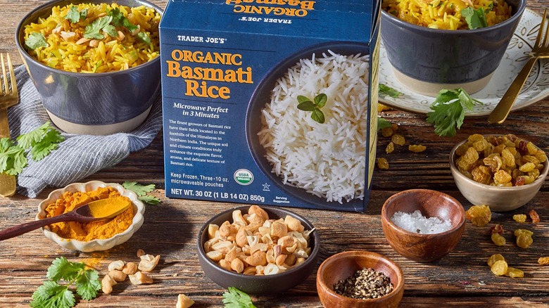 Box of Trader Joe's frozen organic basmati rice surrounded by bowls of spices, nuts, dried fruit, rice dishes