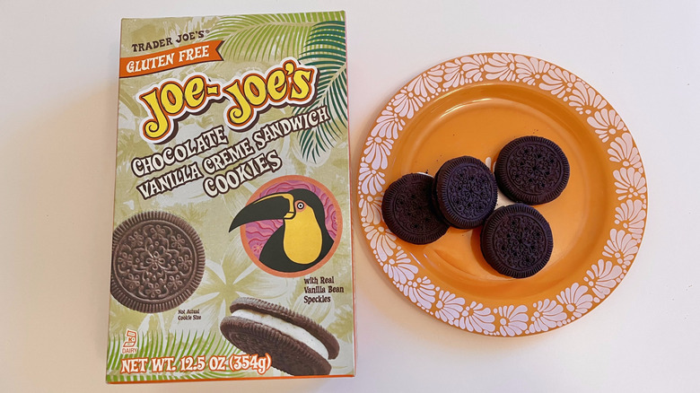 Four Joe-Joe's Chocolate Vanilla Creme Cookies on an orange plate with a box of cookies on the side