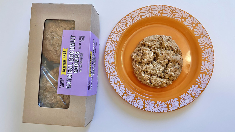 One Oatmeal Coconut Cookie with Raisins on a plate next to the whole box of cookies