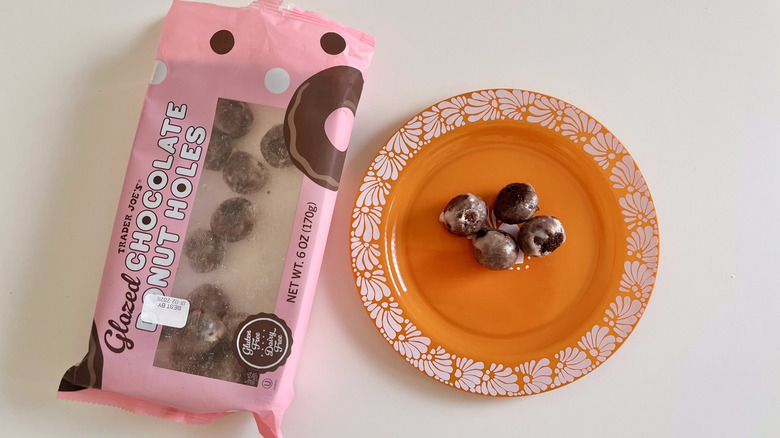 Four donut holes on small plate and a box of Trader Joe's glazed donut holes