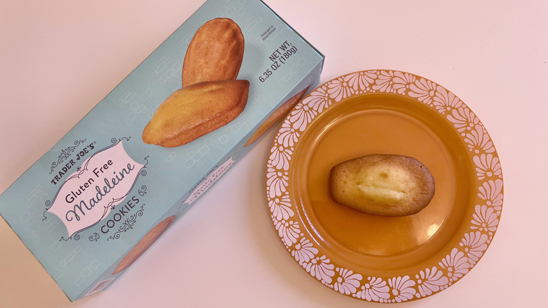 One Gluten Free Madeleine Cookie on plate and a box of Trader Joe's madeleines next to it