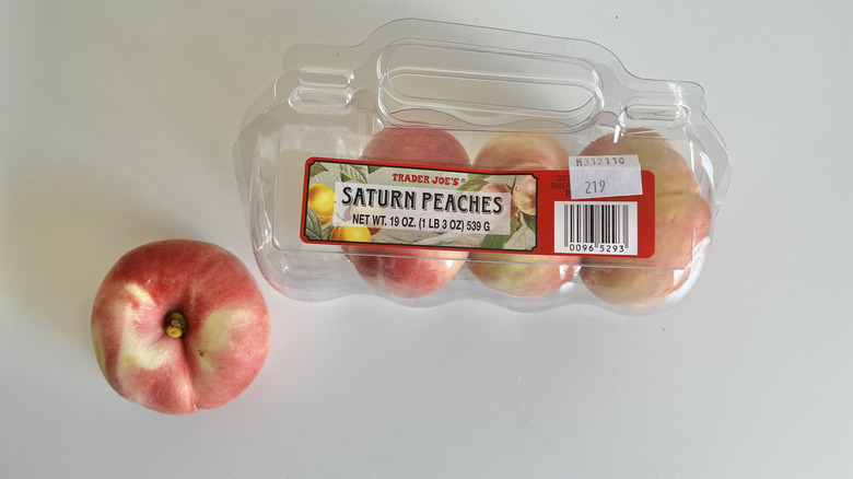 Three Trader Joe's saturn peaches in a package with one loose next to it