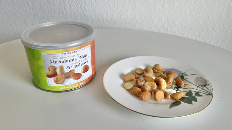 A tin of honey roasted nuts next to a small saucer of nuts
