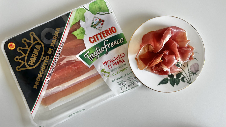 Prosciutto di parma package on a table next to a small bowl of prosciutto