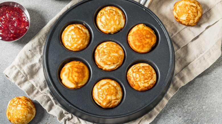 Aebleskiver pan with jam and a towel beneath