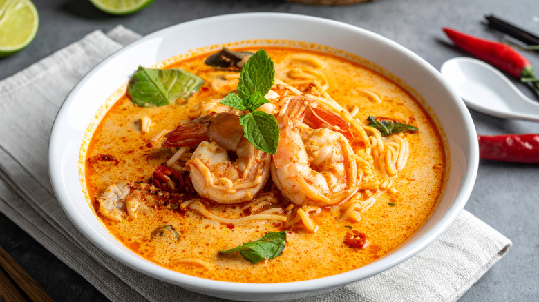 Bowl of Malaysian laksa noodle soup with shrimp and fresh mint garnish