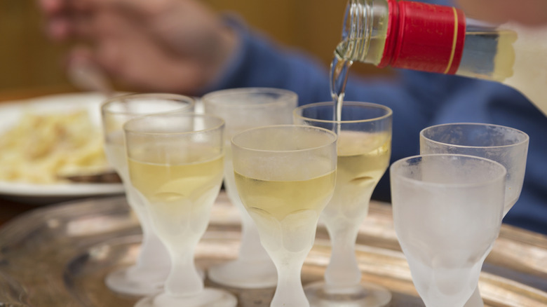 Aquavit being poured into frosted glasses on tray
