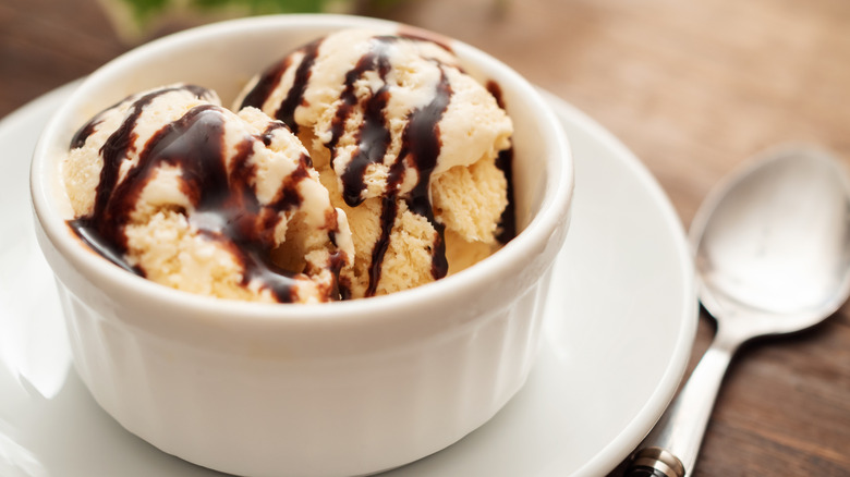 A ramekin with vanilla ice cream and chocolate sauce