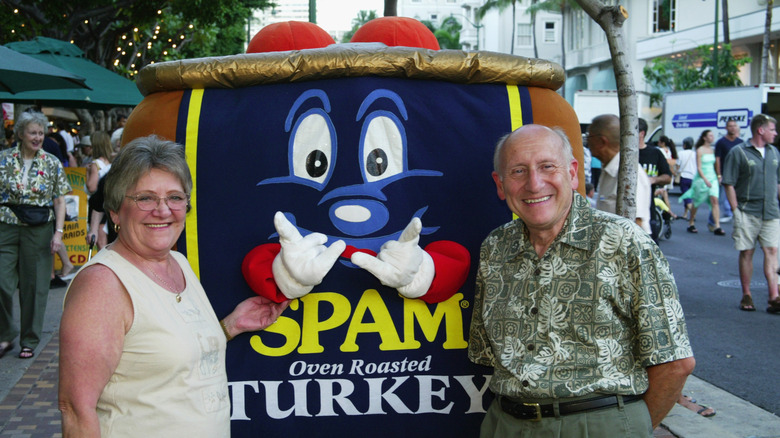 A man and a woman pose with a person in a Spam costume during the Waikiki Spam Jam