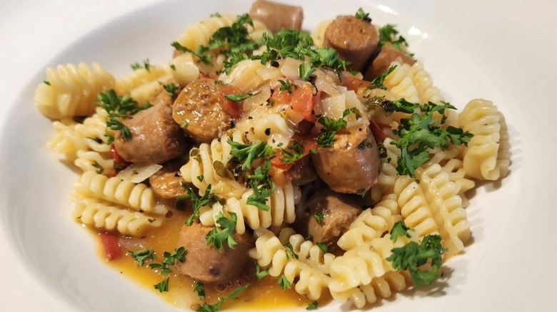 Radiatori pasta with a sausage and tomato sauce, topped with fresh parsley