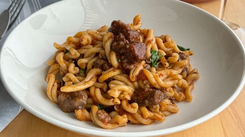 Bowl of priest stranglers served with a meaty sauce and herbs