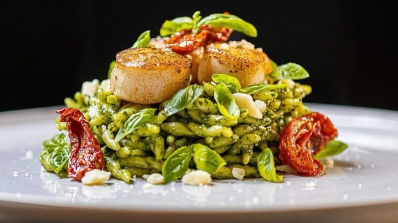 Beatifully plated trofie with basil, sun-dried tomato, and scallops