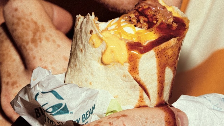 Person eating messy Taco Bell Burrito and getting it all over their hands