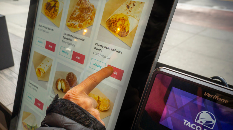 Finger clicking the Add button on a Taco Bell kiosk