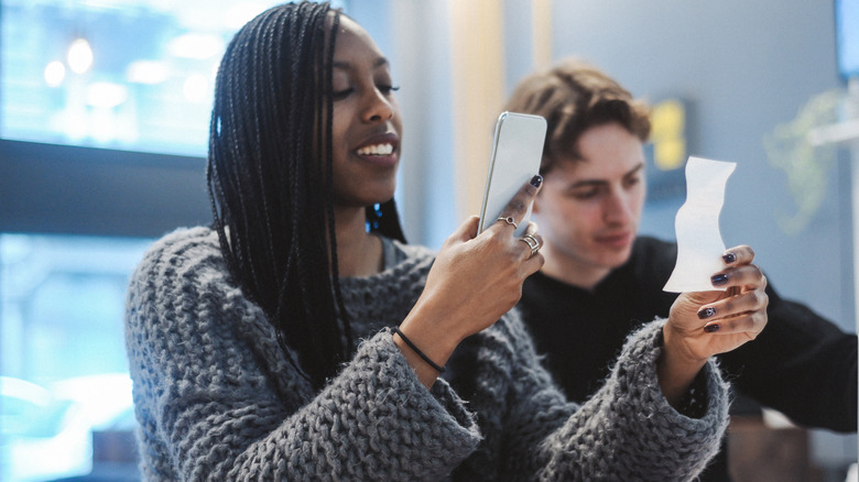 Woman using phone to photograph her receipt