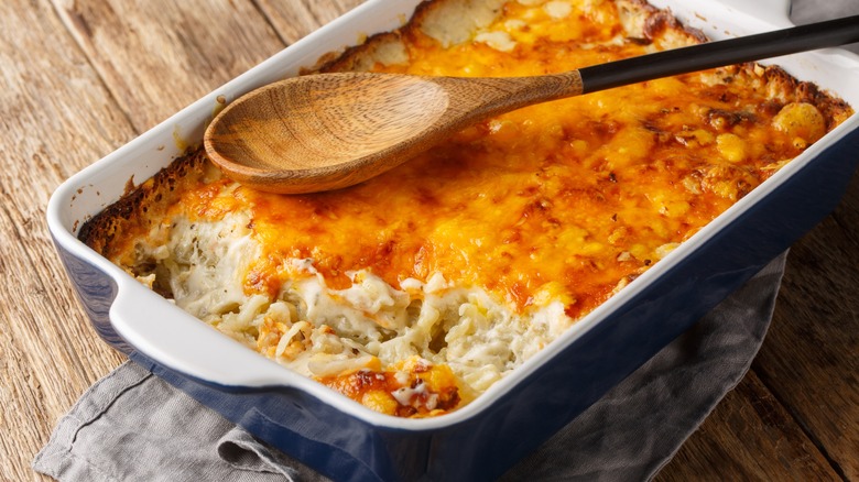 Hash brown casserole in baking dish with wooden spoon resting on top