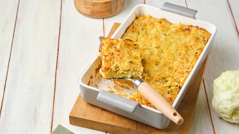Cabbage casserole in baking dish, with portion being scooped out