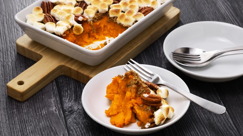 Marshmallow and pecan-topped sweet potato casserole in baking dish and on plate