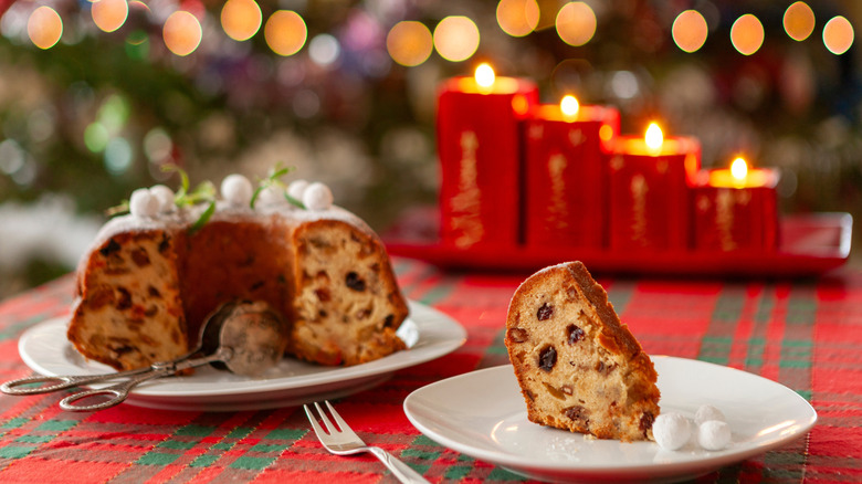A fruitcake and a slice of fruitcake on table with Christmas decorations