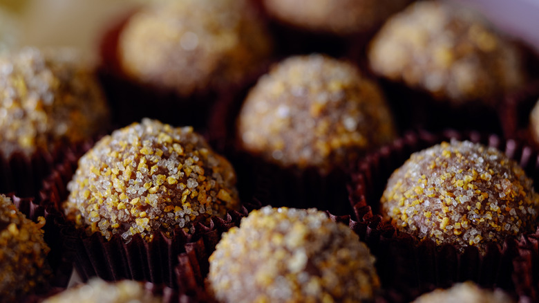 A close-up of rum balls coated with sugar in paper pastry cups