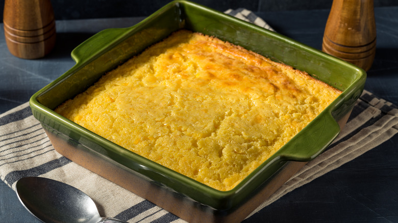 Spoon bread in a green casserole dish on a striped napkin