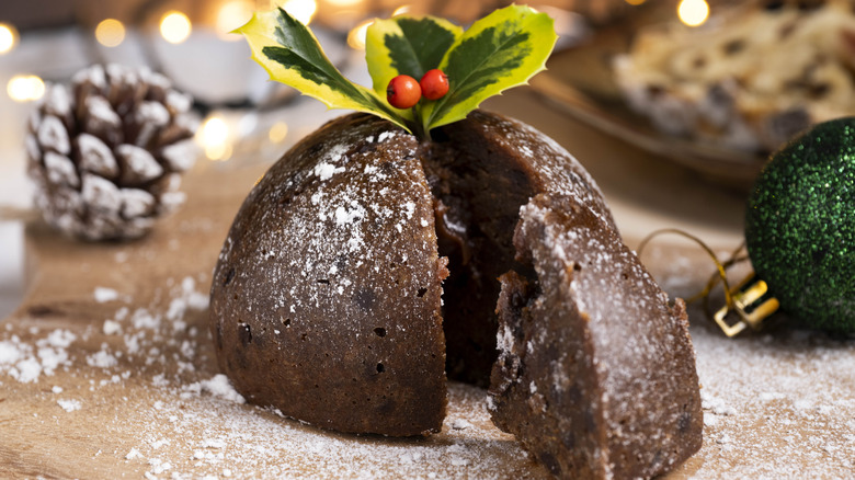 A christmas plum pudding with a holly branch garnish and a slice removed