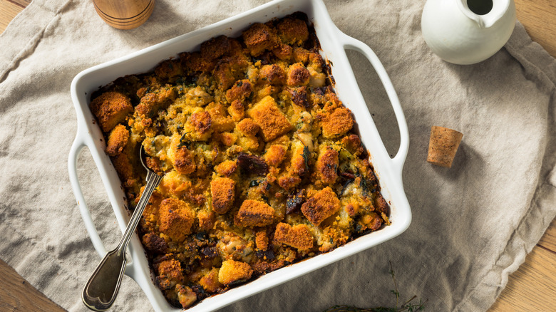 Oyster stuffing in a white casserole dish on a rustic cloth