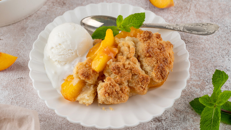 Peach cobbler on plate with ice cream and spoon