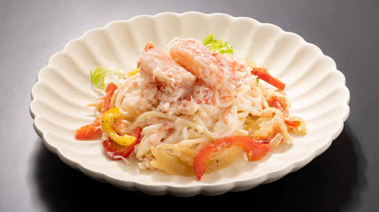 A white bowl of angel hair pasta topped with crab meat