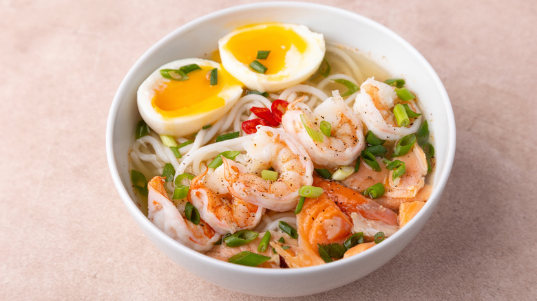 A bowl of ramen topped with shrimp, egg, and green onions