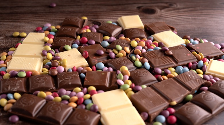 A variety of chocolate and candy pieces on a wooden background.