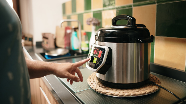 Hand pressing a button to start an automatic pressure cooker