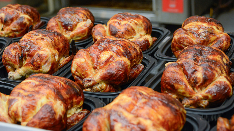 Rows of rotisserie chickens sitting in plastic trays waiting to be sold