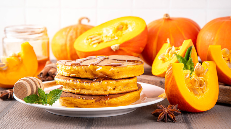 A plate of pancakes surrounded by pumpkins