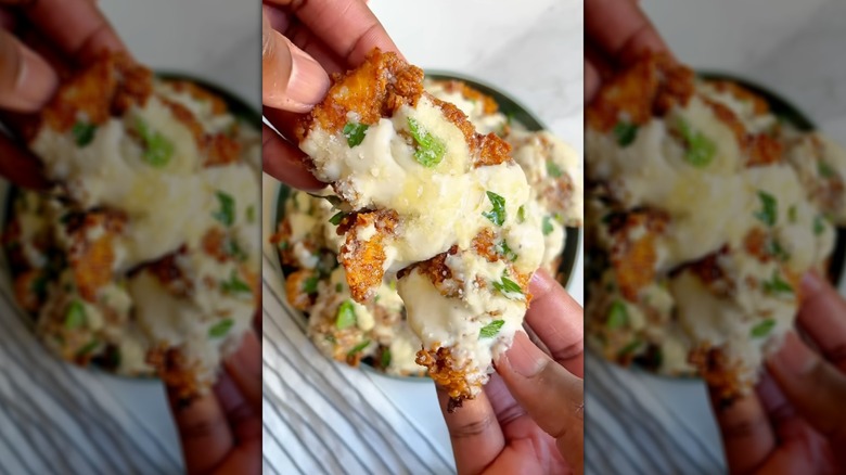 Hands holding cheese and herb-loaded chicken tender