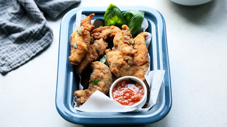 Chicken tenders in blue rectangular dish with small bowl of arrabbiata dipping sauce