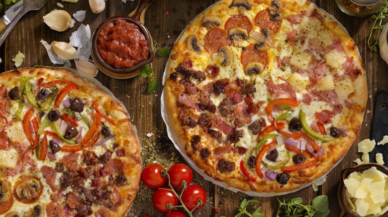 Two pizzas topped with a different combination of ingredients in each quadrant of the pizza