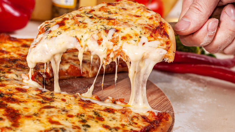 A man serving a slice of pizza that is dripping with melted cheese