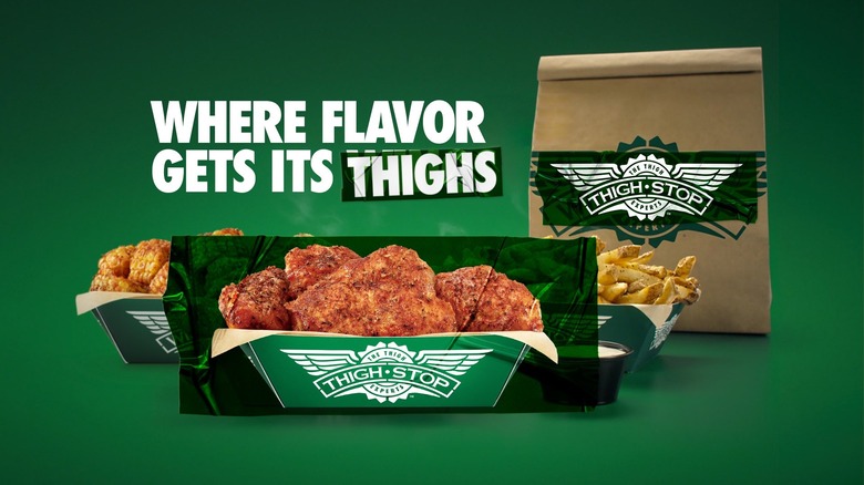 A box of seasoned chicken thighs, fries with dip, and corn displayed in front of Thighstop branding and a promotional slogan