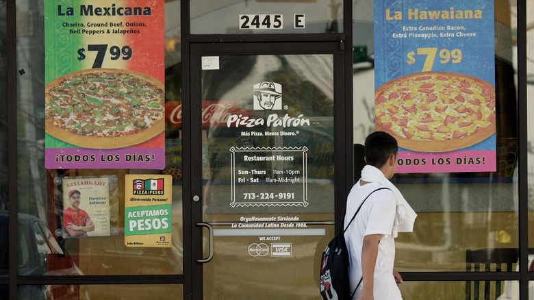 A boy walking past Pizza Patrón during the day